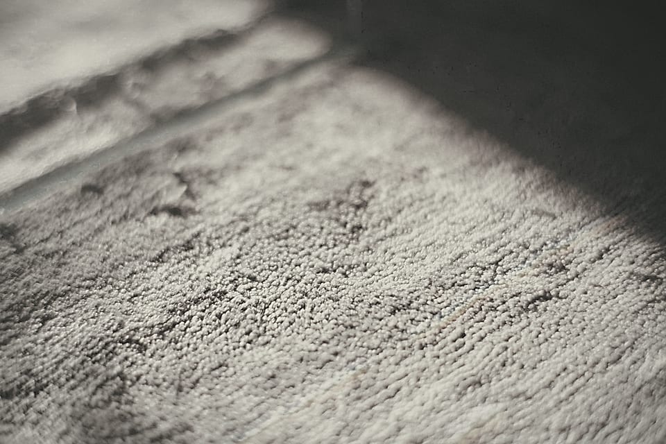 Tapis clair et plinthe dans un rai de lumière