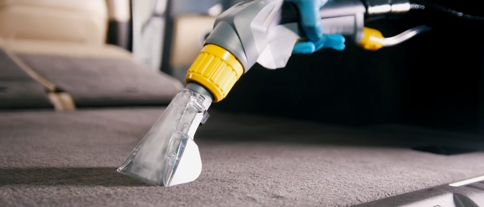 Nettoyage par extraction — la buse passe sur un textile gris